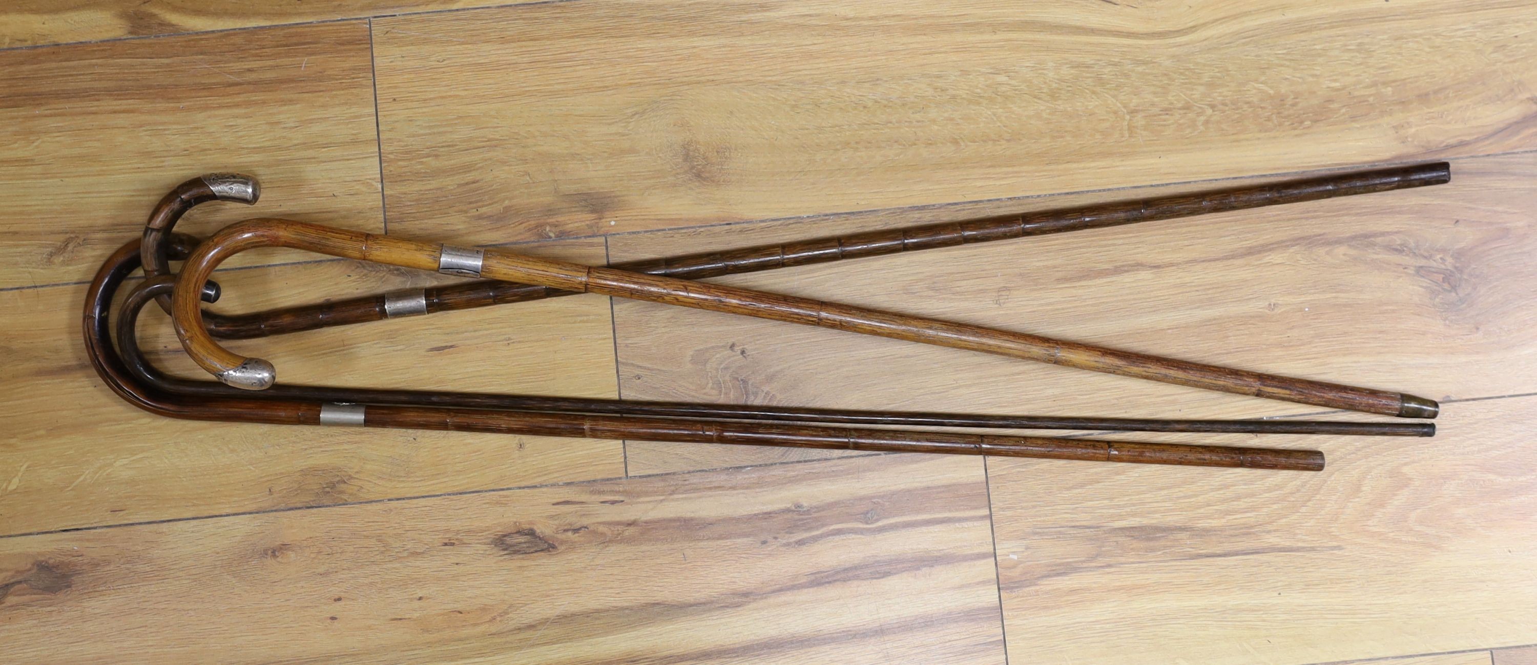 Four silver mounted walking canes, longest 85 cms.